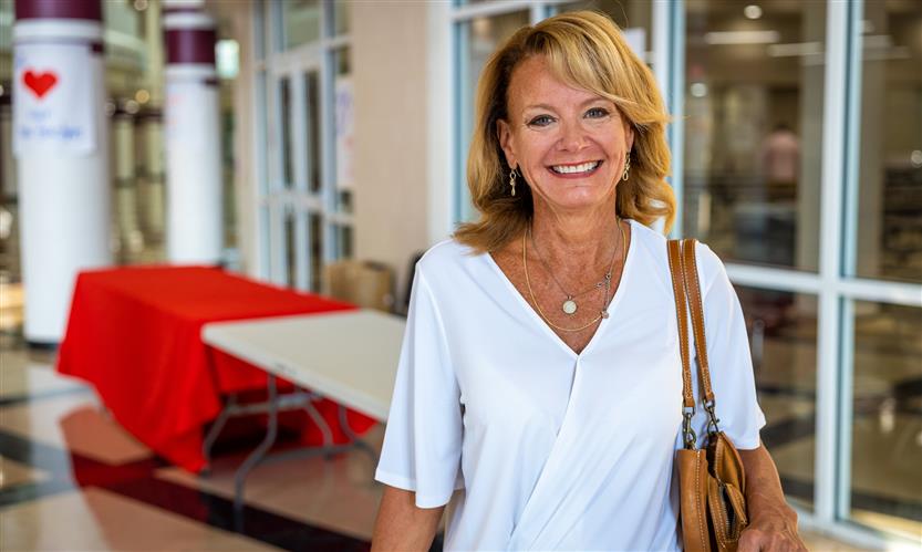 A woman wearing a light blue shirt smiles in the hallway of a school
